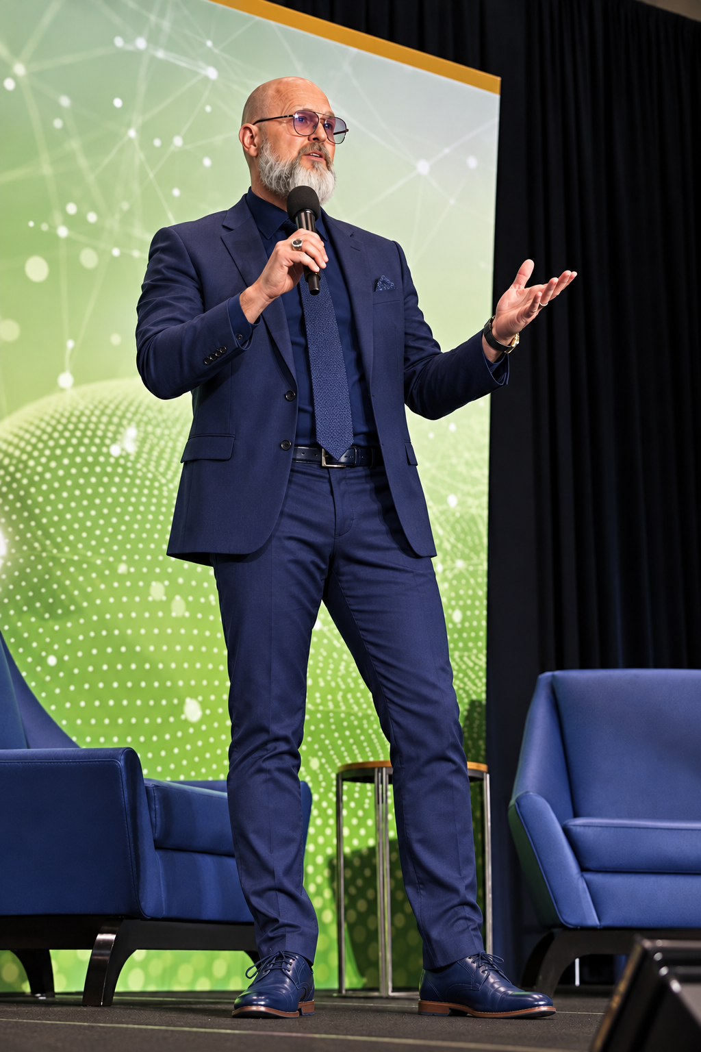 Mark A. Grainger speaking on stage in a navy suit